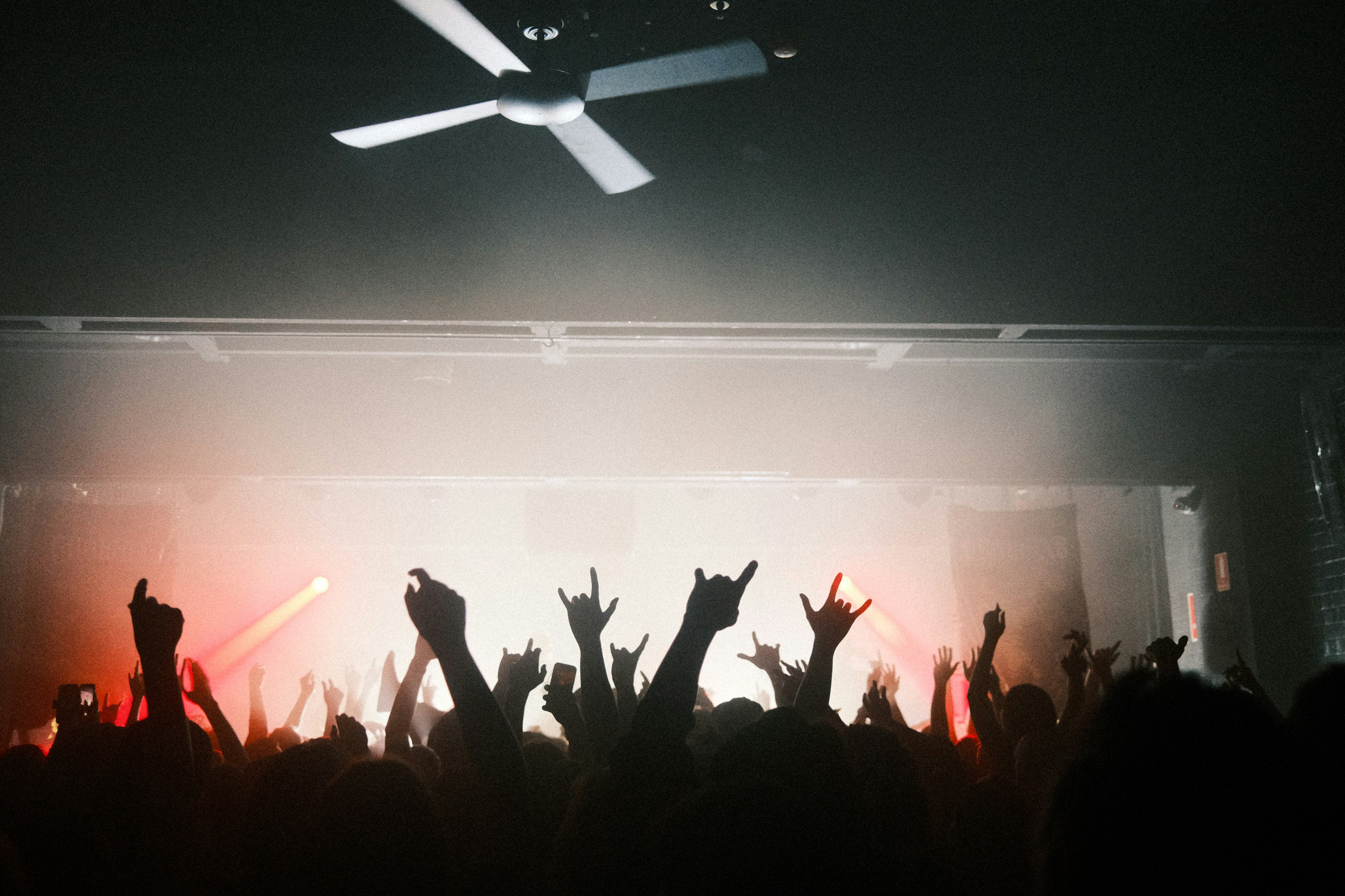 Concert crowd with hands raised against dramatic stage lighting